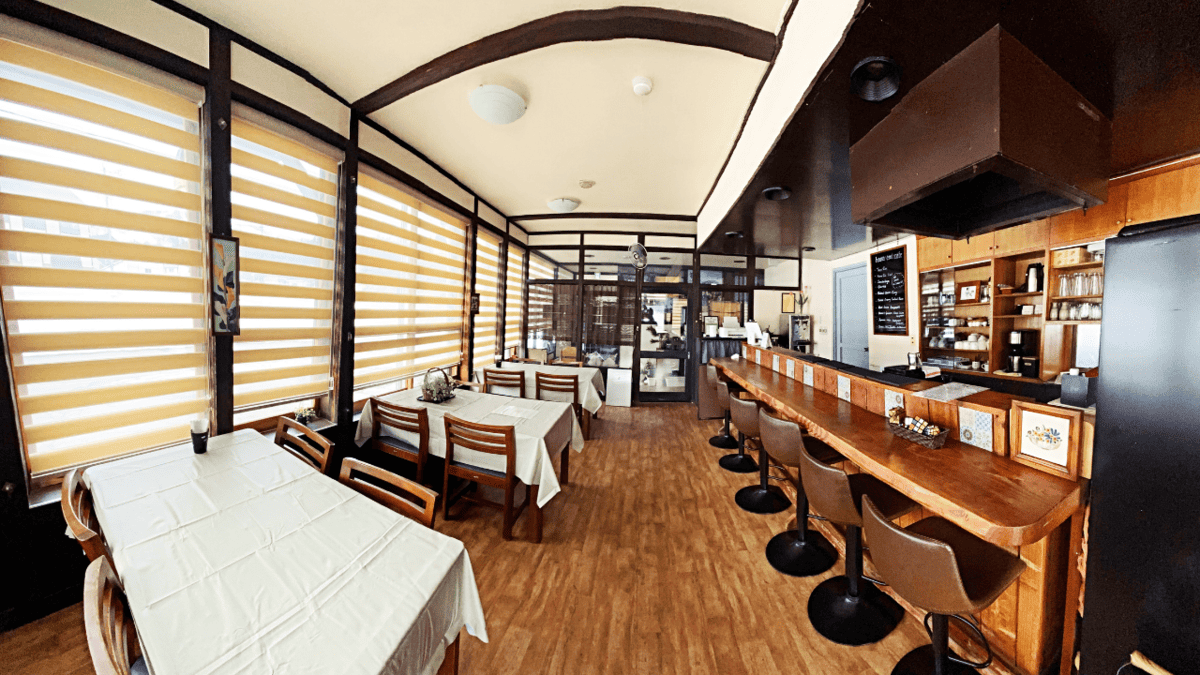 The interior of a small Japanese cafe with one row of tables and a counter. 